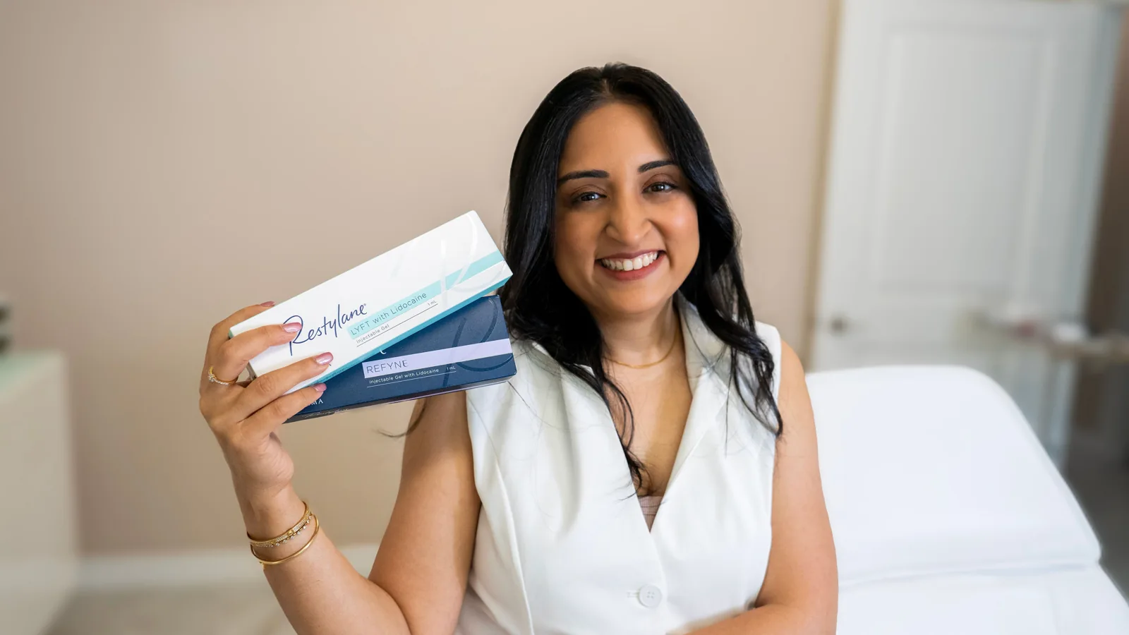 AYUR Aesthetics practitioner smiling and holding aesthetic treatment products