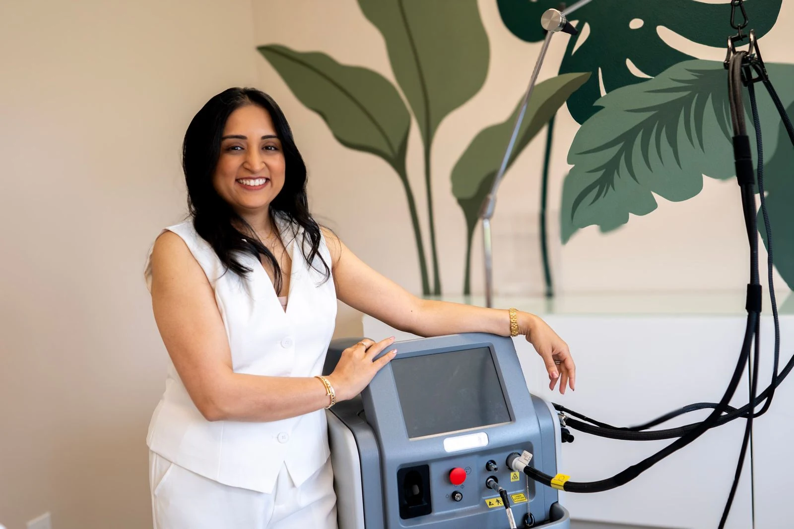 Practitioner standing beside a laser treatment machine at AYUR Aesthetics